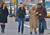 陌生人有助于一个老人在纽约市的街道上走路。