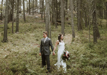 一对穿着婚纱和西装的夫妇站在森林里。