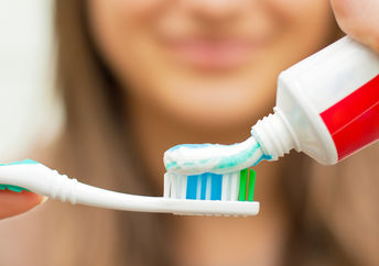 把牙膏放的妇女在牙刷。