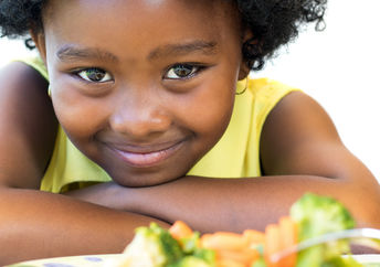 一个年轻女孩拿着一盘健康的食物微笑着。