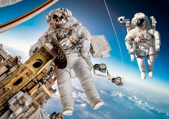 在外层空间的国际空间站与两个宇航员漂浮在外面。